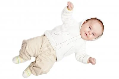 A smiling person wearing a newborn and toddler outfit holds a baby in their arms.