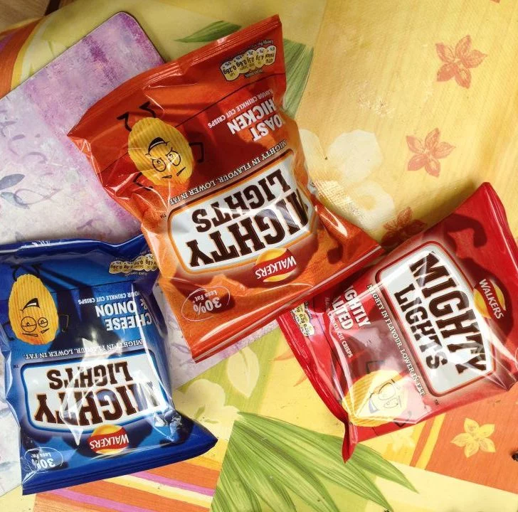 This image is advertising a product, Mighty Lights Crinkle Cut Crisps, which are lower in fat and have 30% less fat than regular Walkers Crisps.