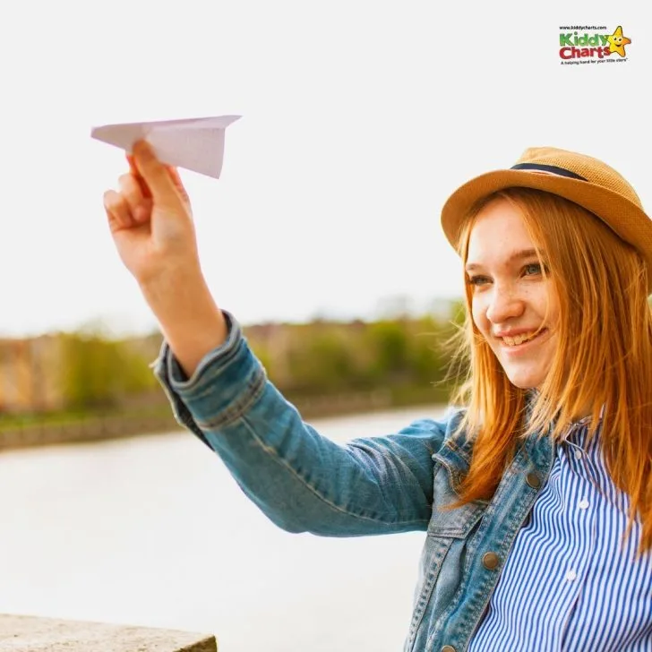 A young person wearing a fashionable sun hat smiles outdoors.