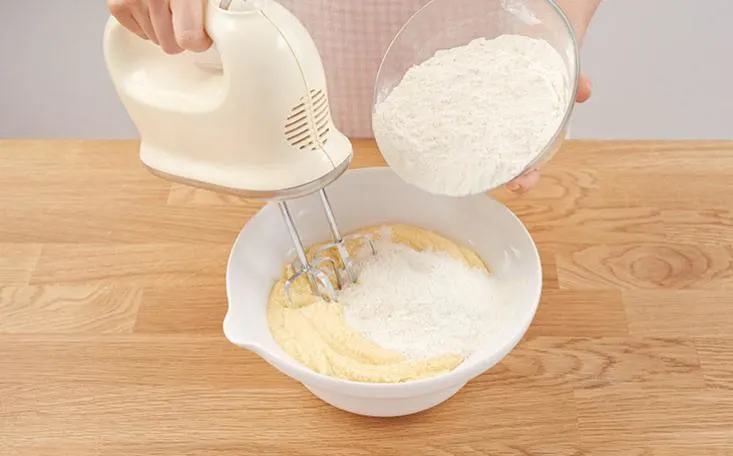 A bowl of dairy, powder, thickening agent, wheat flour, rice flour, all-purpose flour, and whole-wheat flour is being mixed together indoors to create a food flour.