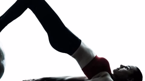 A person is demonstrating balance and physical fitness by performing a yoga pose with their knee, hip, and elbow supported by active pants and a yoga mat.