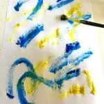 A child is painting a colorful drawing with art paint.