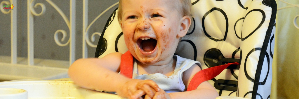 Weaning your baby - toddler at a high-chair covered in food.