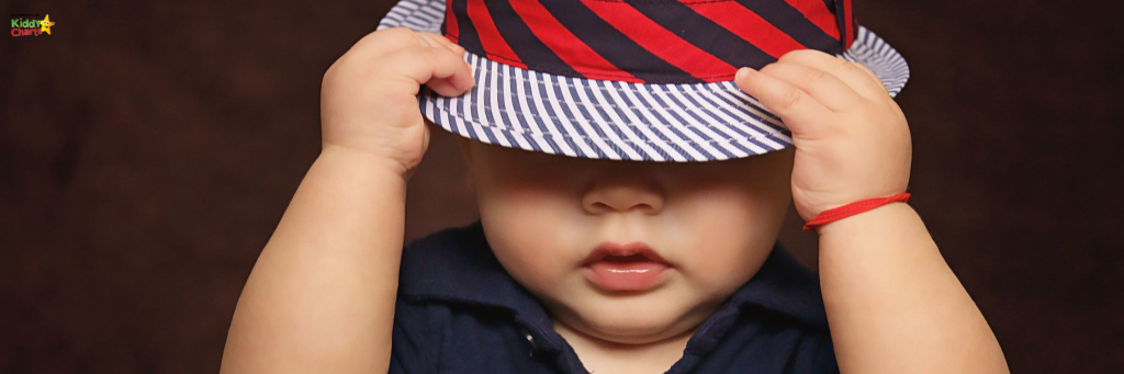 If you want to make toddler parenting a little easier, it’s a good idea to try and see things from their perspective. Toddler pulling a red hat over his face.