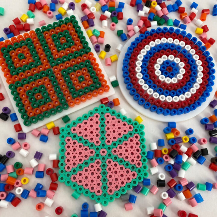 A craft artist is creating a colorful pattern with beads and charts.