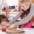 A person is sitting at a table with a potter's wheel in front of their, cutting text onto a human face on the wheel.