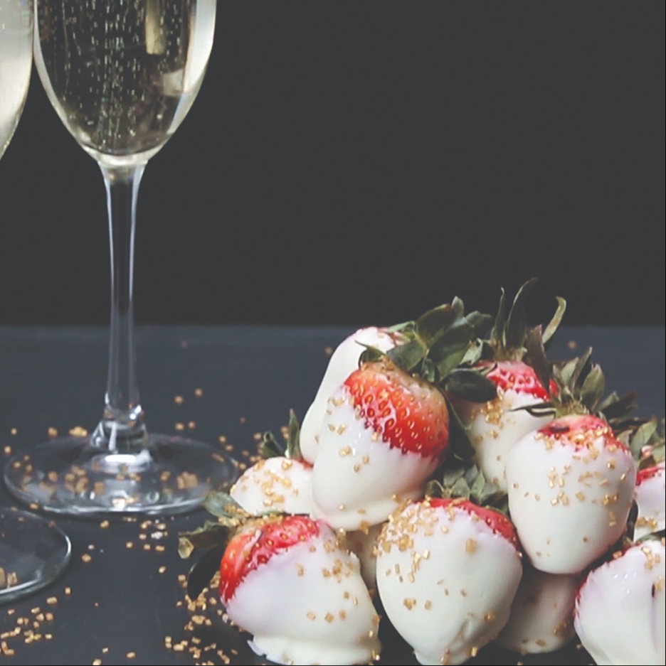 A white table is set with plate, tableware, stemware, wine glass, champagne stemware, and a strawberry, creating a beautiful culinary art display of food, drinkware, and wine.