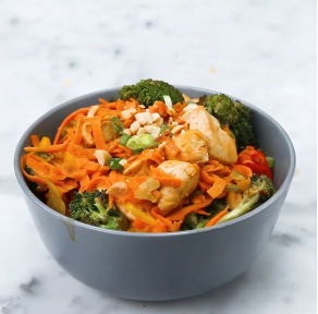 A chef is stir-frying a vegetarian dish of shrimp, carrots, and other vegetables in a bowl, creating a delicious side dish to accompany a salad.
