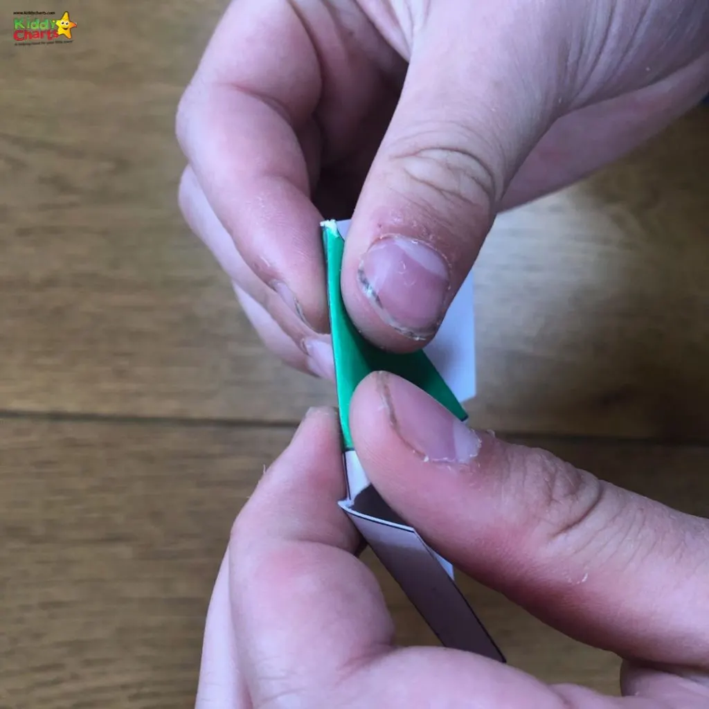 A person is using scissors to trim their thumb nail with office supplies spread out on their hand.