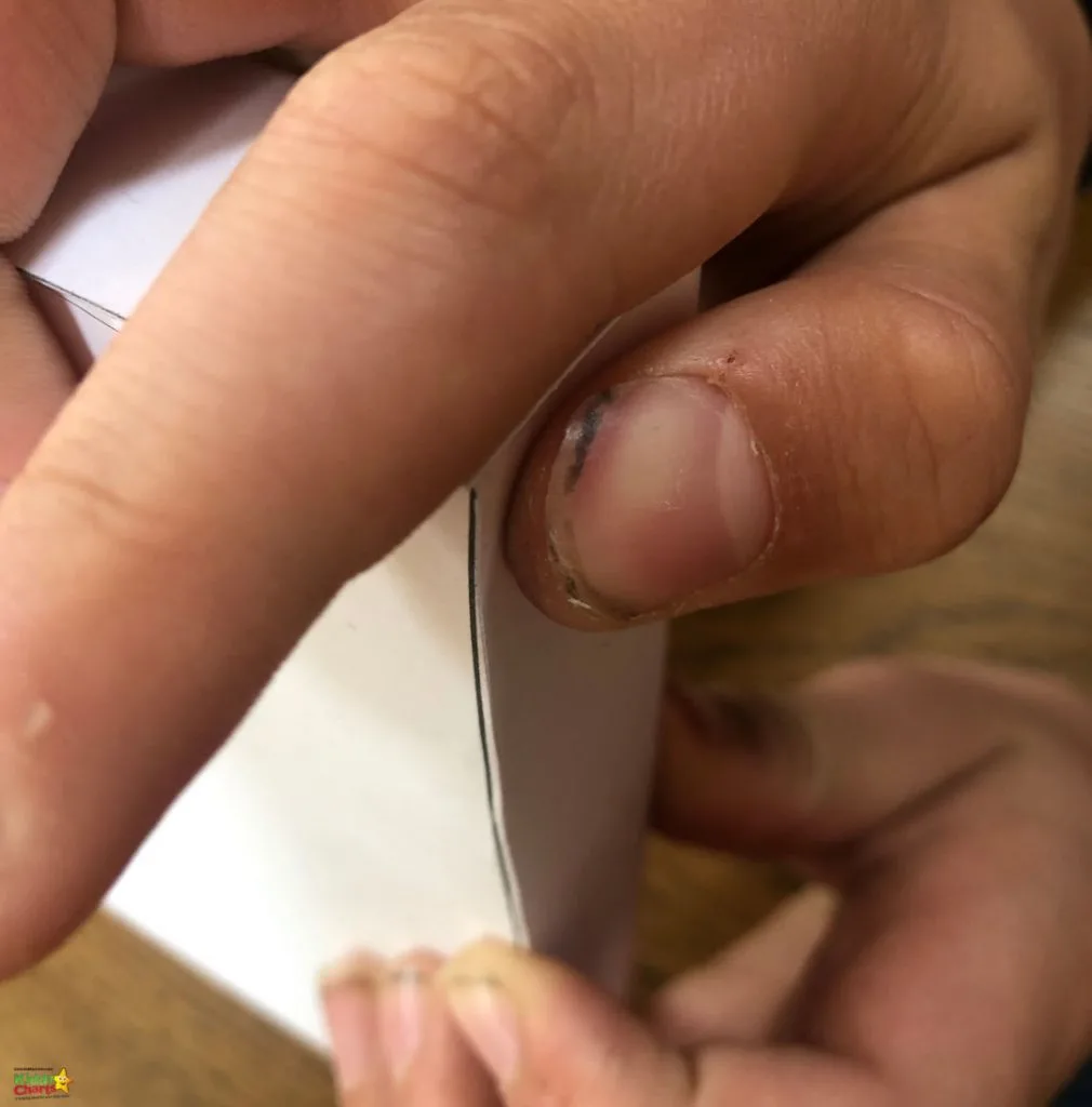 A person is getting a manicure on their hand, with their thumb and finger veins visible, while wearing a band-aid on their wrist, indoors.