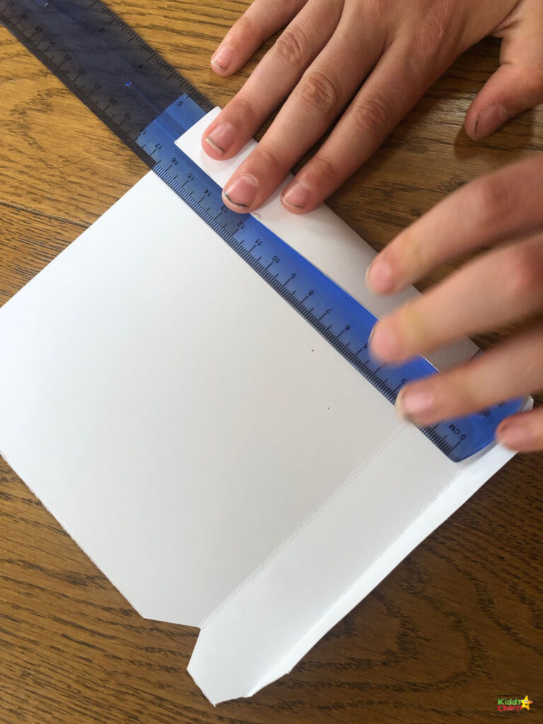 A person is cutting a paper product with a finger and a nail while holding office supplies in a hand inside an indoor stationery.