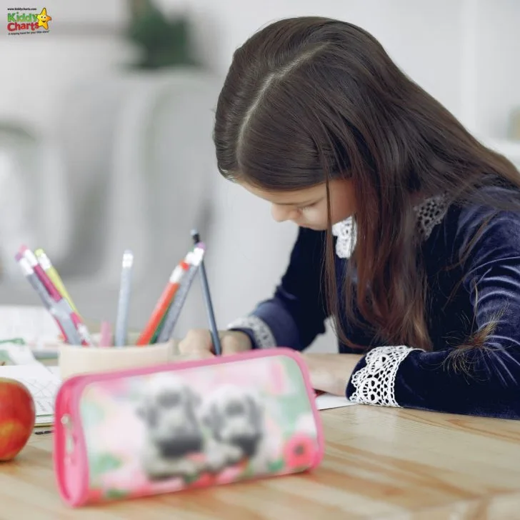 A young person and person are cutting out colorful child art with office supplies at a table while learning together in an indoor setting.
