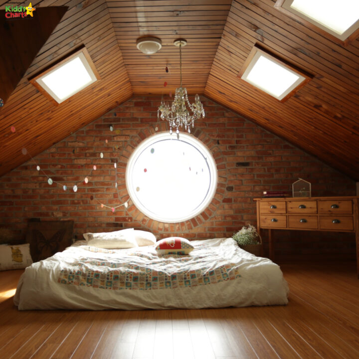 A cozy attic room with hardwood floors, wooden beams, and furniture made of lumber is illuminated by the natural light coming through the ceiling.