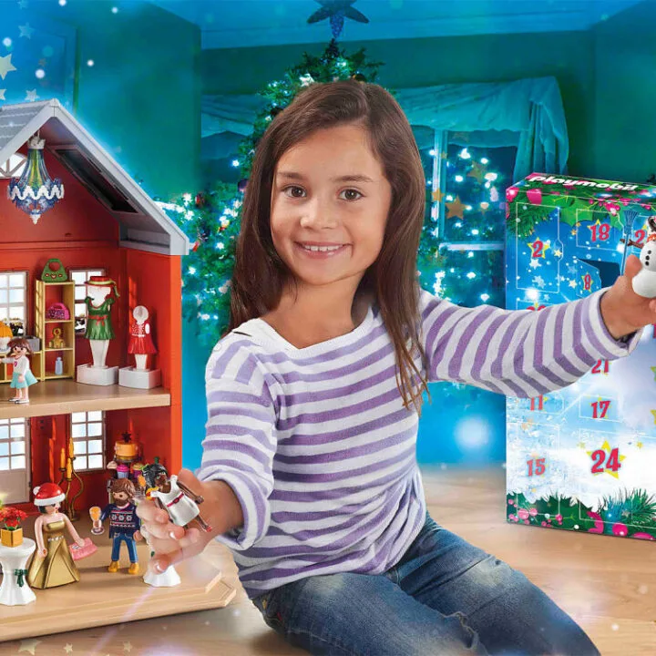 A young person is decorating a Christmas tree inside a cozy house with Playmobil figures.