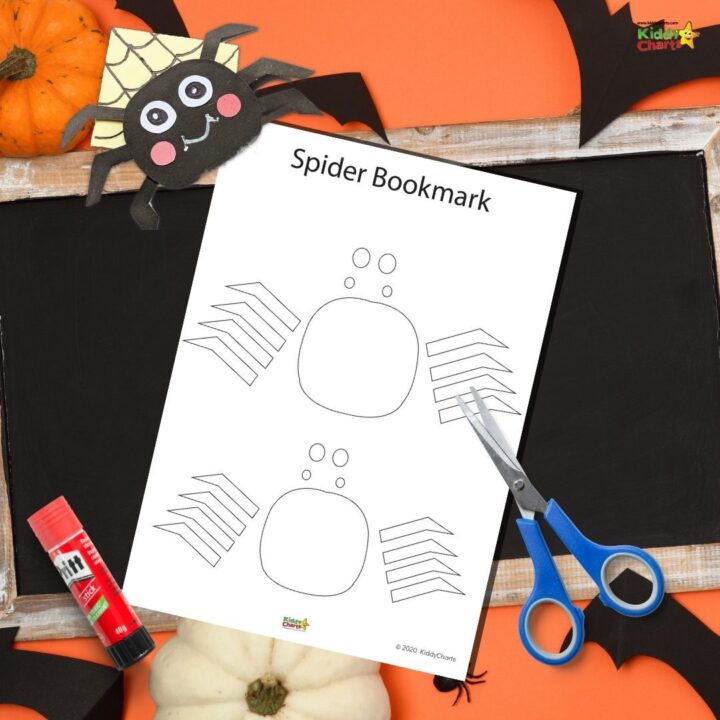 A pumpkin-shaped spider bookmark crafted from orange scissors and office supplies decorates a text book, creating a festive Halloween scene.