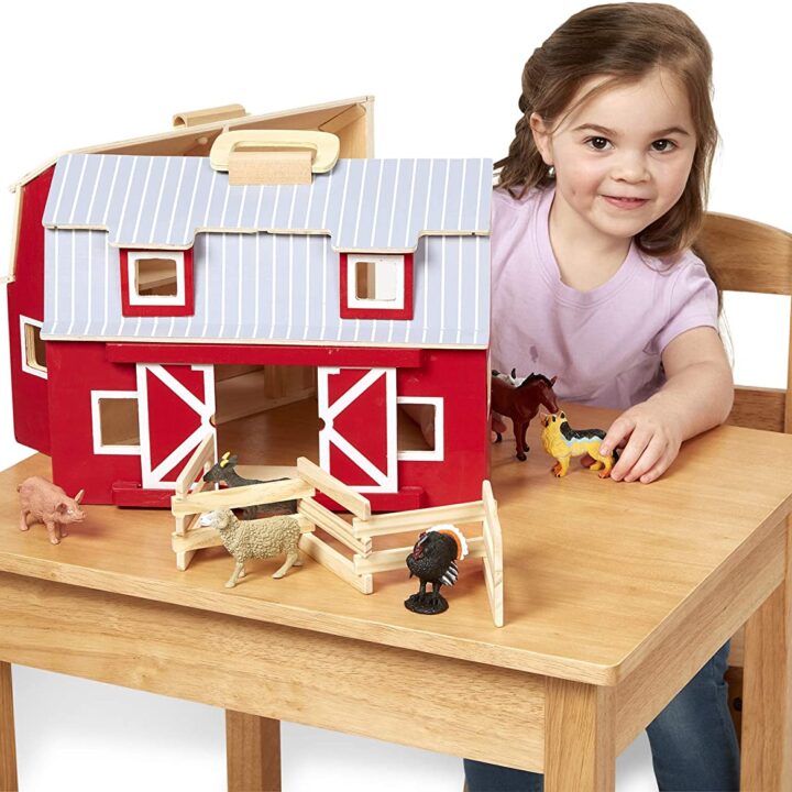 A person sits at a table with a toy house.