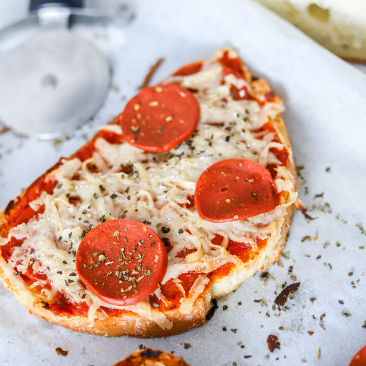 A slice of California-style pizza with pepperoni, cheese, and tomato sits on a flatbread dish, baking in an indoor oven and ready to be enjoyed as a delicious Italian-style fast food cuisine.