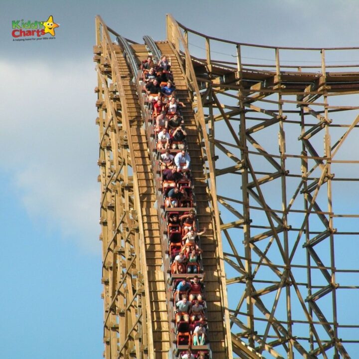 A roller coaster ride whizzes through the sky of an outdoor amusement park, providing a thrilling tourist attraction for fair-goers at the theme park.