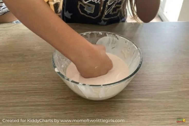 A person is actively mixing ingredients in a wooden bowl inside a cozy indoor setting.