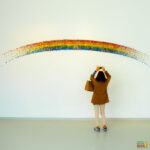 A person stands in front of a rainbow.