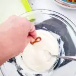 The spoon is held over a bowl of ice cream.