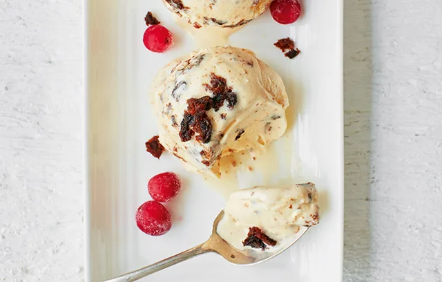 A spoon scoops up a scoop of gelato topped with fresh berries, creating a sweet and delicious frozen dessert snack in the kitchen.