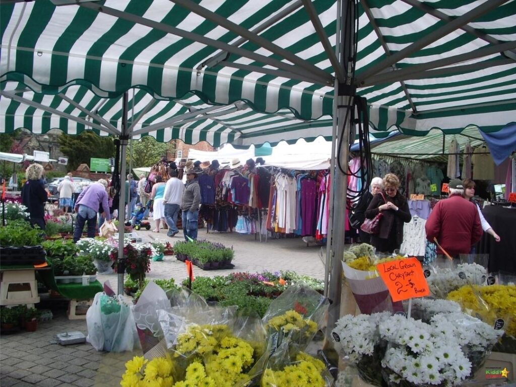 People are standing in an outdoor marketplace, trading and selling local grown flowers, plants, and vegetables at the bazaar flea market.