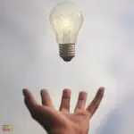 The hand holds a light bulb.