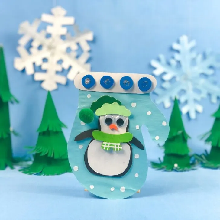 The snowman stands in front of trees in the winter landscape.
