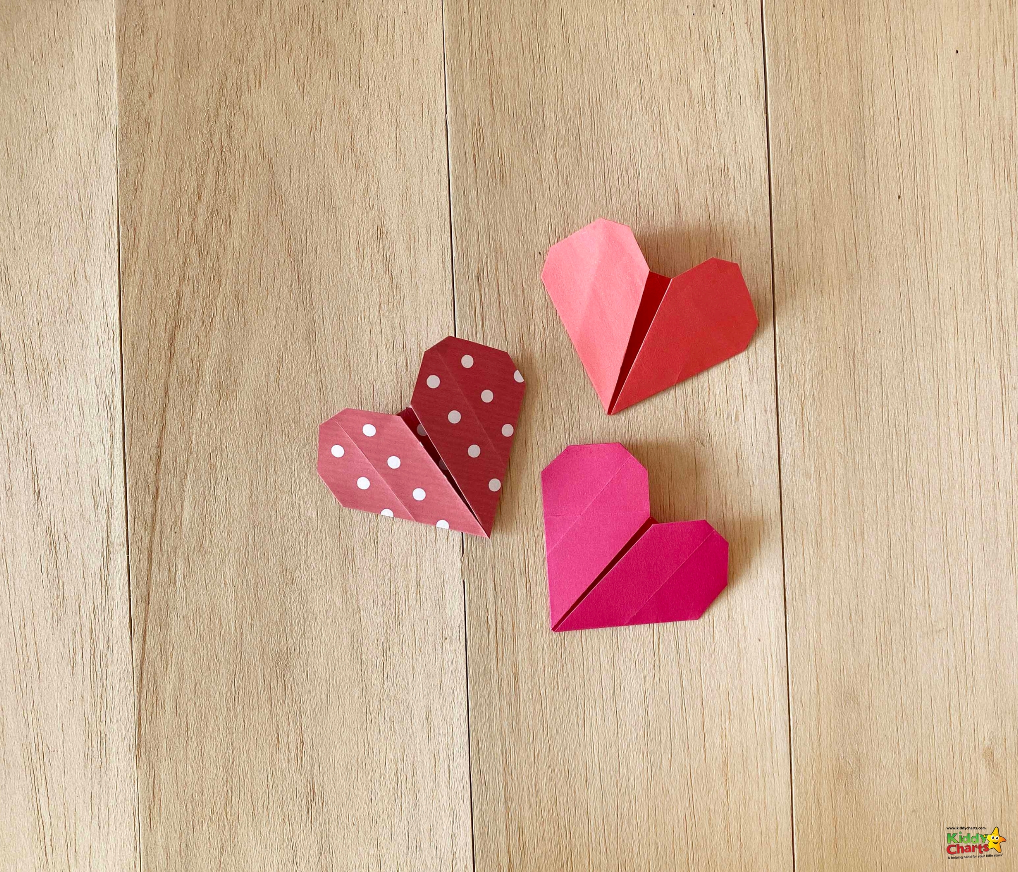 A child is crafting a pink heart out of art and construction paper for Valentine's Day.