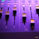 A mixing console is actively producing music with a variety of electronic components.