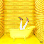 A person is relaxing in a yellow bathtub in a bathroom indoors.