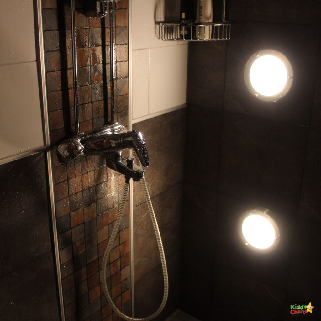 A tripod stands in the middle of a shower, reflecting a bright light off the mirror.