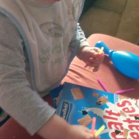 A toddler and baby play happily indoors, wearing matching baby and toddler clothing.