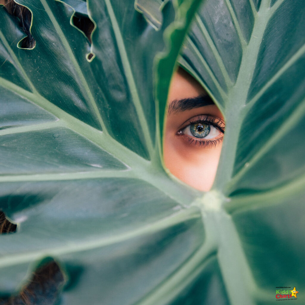 A young person with green eyes is holding a leafy vegetable in front of their face, creating a playful expression.