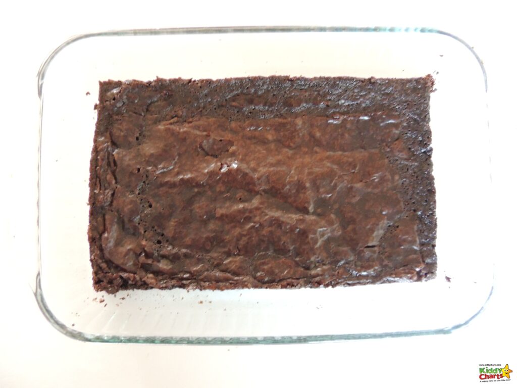 A freshly-baked chocolate cake with cocoa solids and chocolate brownie pieces on a plate, ready to be enjoyed as a delicious snack.