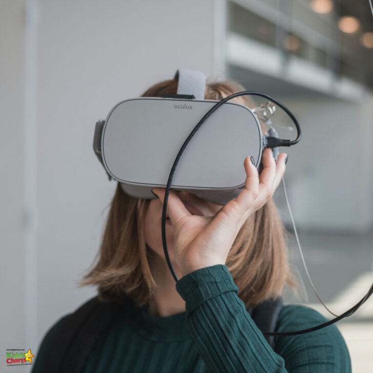 A person is wearing an Oculus virtual reality headset, covering their eyes. The environment is indoor with a bright, modern background.