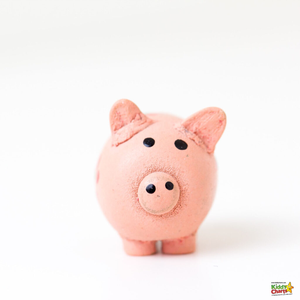A small pink ceramic piggy bank with a slot on top stands against a white background. It's a simple and cute representation of savings.
