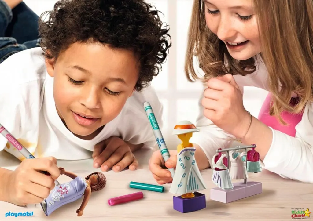 Two children are happily coloring and playing with Playmobil toys, surrounded by markers and doll clothing accessories on a bright background.