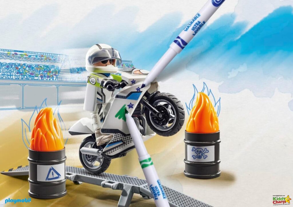 A Playmobil figure is riding a stylized motorcycle, leaping over barrels with flames. Background resembles a drawn stadium and sky. It's a toy advertisement.