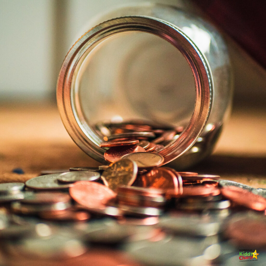 A glass jar tipped over, spilling numerous shiny copper coins onto a wooden surface. Focus is sharp near the opening, soft in the background.
