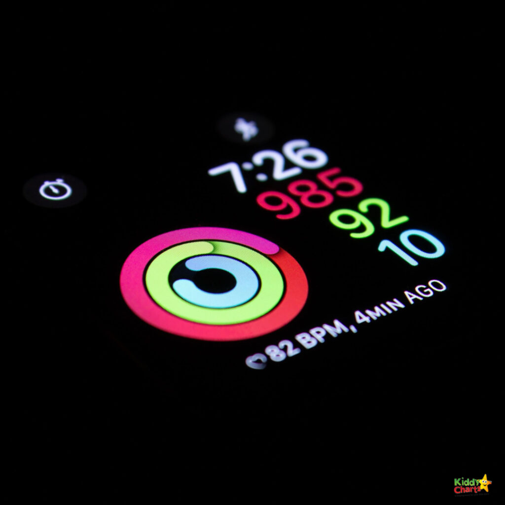 This image shows a close-up of a smartwatch display with colorful activity rings, heart rate information, and other stats against a black background.
