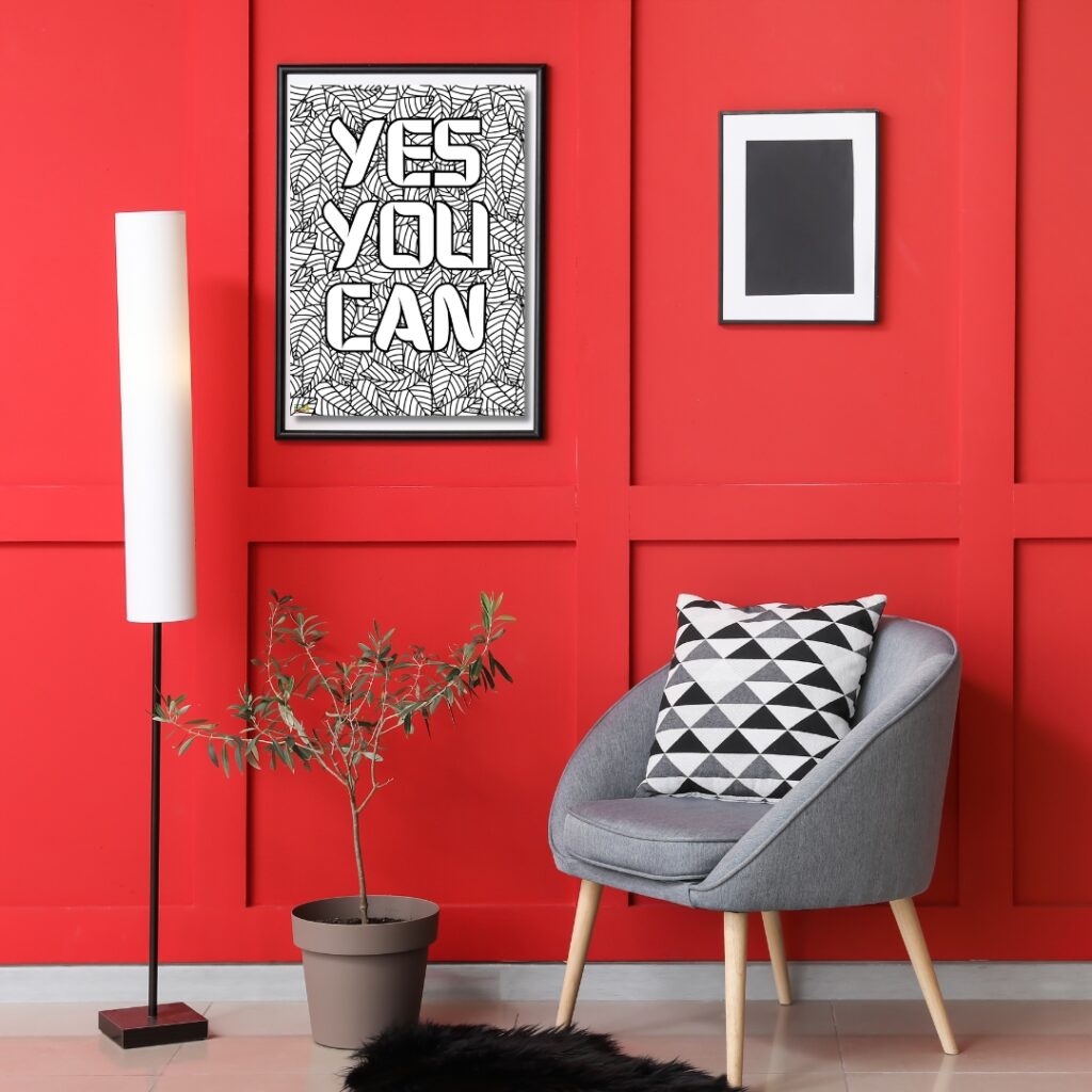 A modern room with vibrant red walls features a motivational framed poster, a sleek armchair with a geometric cushion, a floor lamp, and a potted plant.