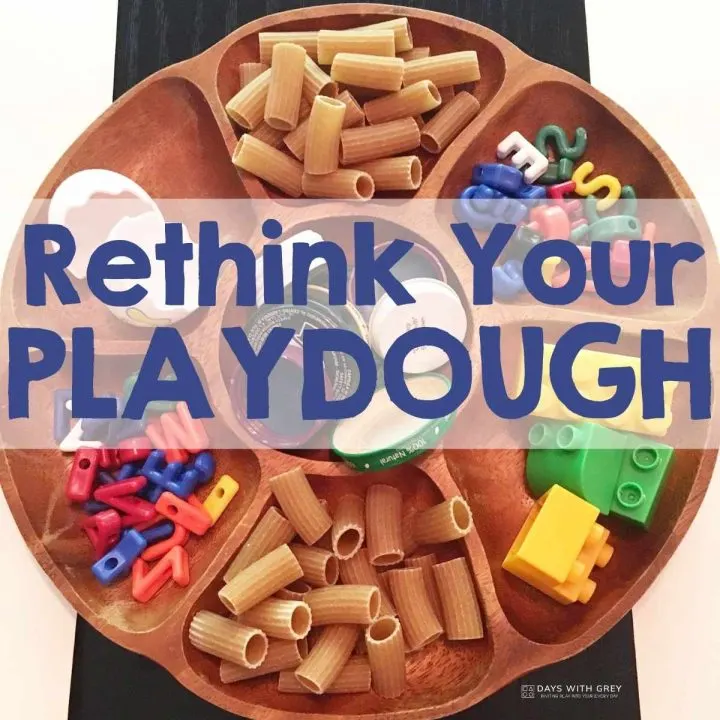 A tray with pasta, colorful plastic pieces, bottle caps, and the text "Rethink Your Playdough" displayed prominently across the center.