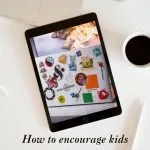 Tablet with colorful stickers, surrounded by a laptop, coffee cup, and vase. Text promotes encouraging kids' creativity with PNG printables at kiddycharts.com.