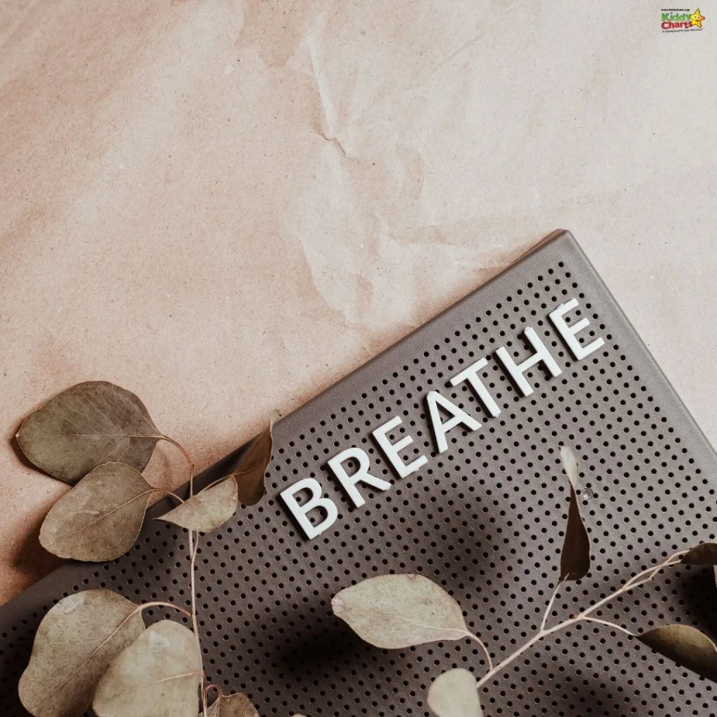 A pegboard spelling "BREATHE" lies on crumpled paper, with eucalyptus leaves scattered artfully around, conveying a calming, mindful atmosphere.