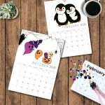 Two illustrated 2026 calendar pages, October with Halloween theme and February with penguins, placed on a wooden table alongside confetti and coffee.