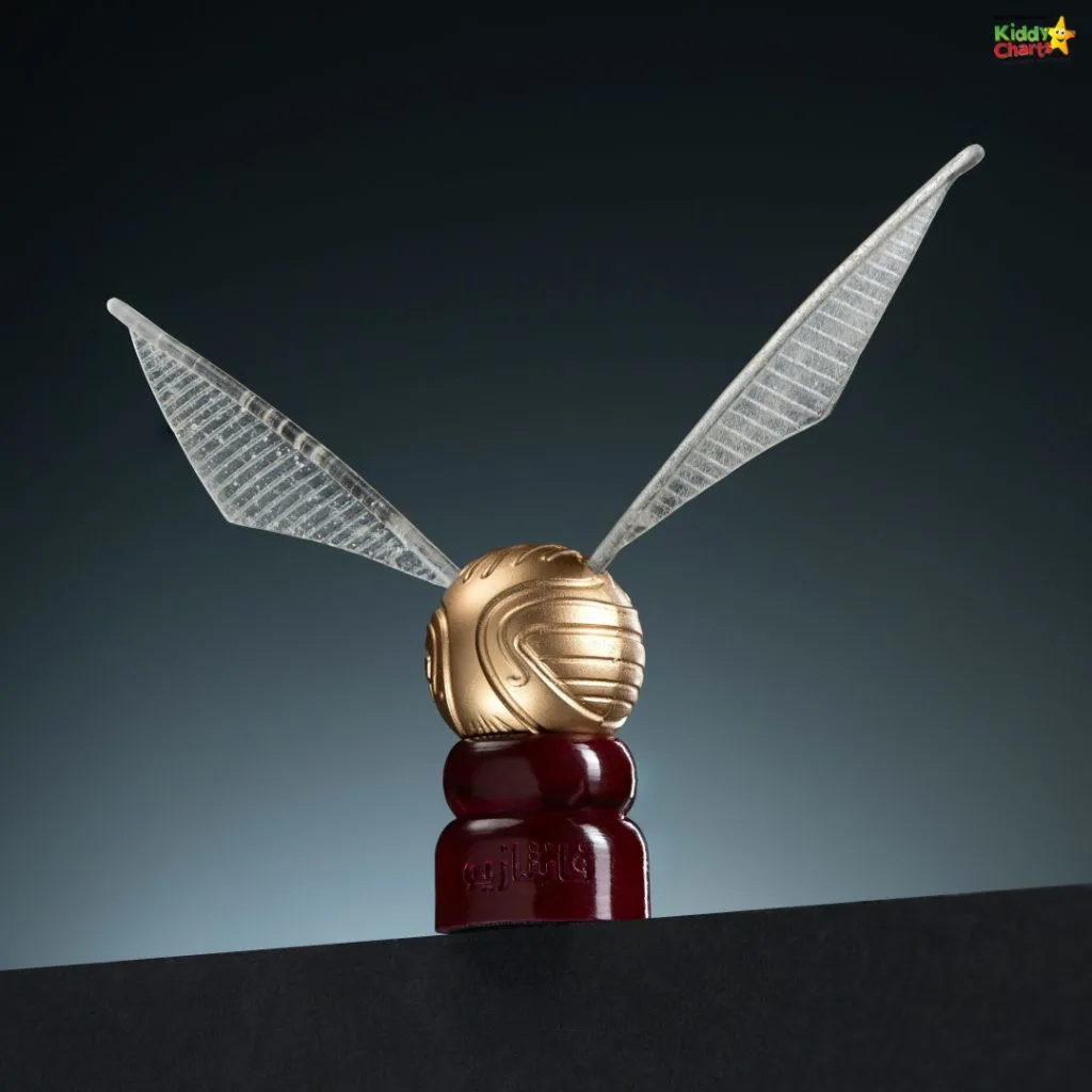 A golden ball with insect-like wings is perched on a red base against a dark background, resembling a flying contraption.