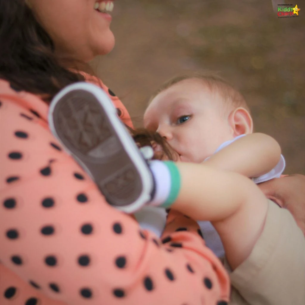 A person gently holds an infant close, with a focus on the baby's shoe and the person's polka dot shirt.