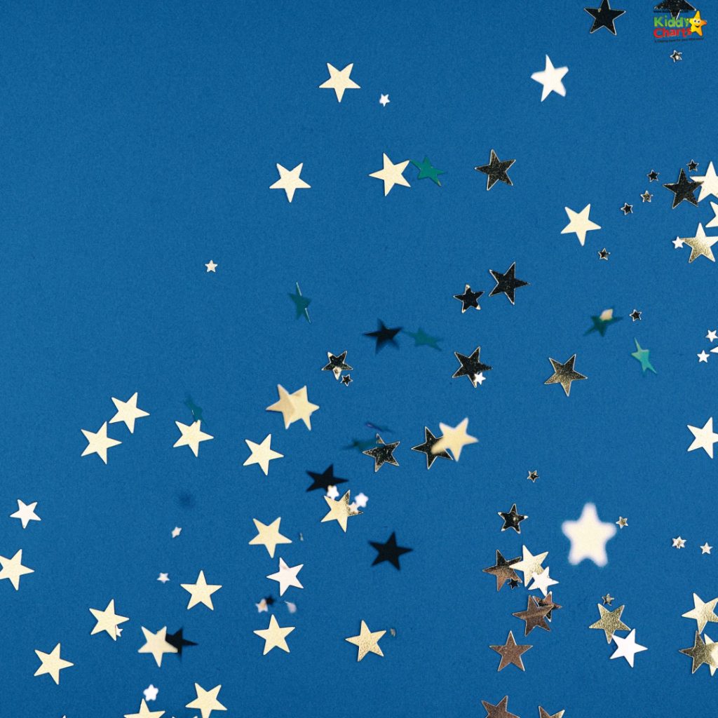 Scattered gold and black star-shaped confetti on a bright blue background, creating a playful and festive atmosphere.